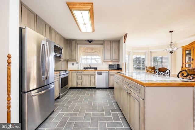 kitchen with a sink, an inviting chandelier, appliances with stainless steel finishes, and light countertops