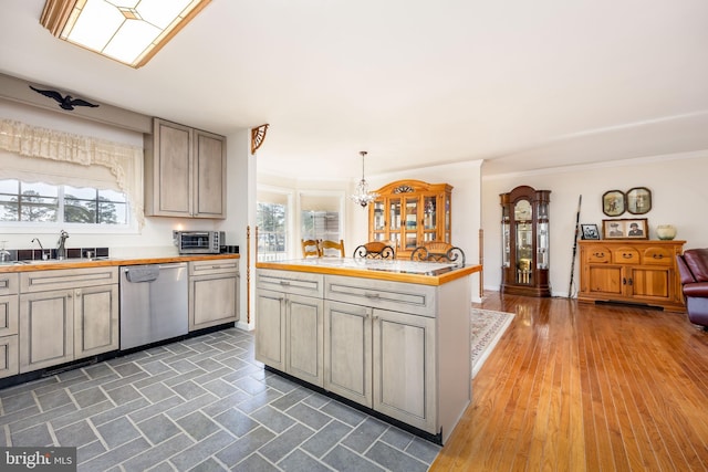 kitchen with a sink, stainless steel dishwasher, a wealth of natural light, and light countertops