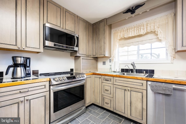 kitchen with tile countertops, appliances with stainless steel finishes, and a sink