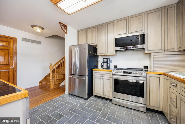 kitchen featuring baseboards, visible vents, butcher block countertops, stainless steel appliances, and crown molding