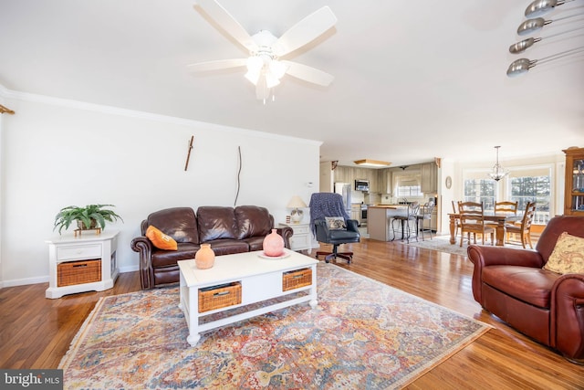 living area with ceiling fan, baseboards, light wood-style floors, and ornamental molding