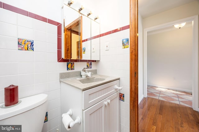 bathroom featuring vanity, tile walls, toilet, and wood finished floors