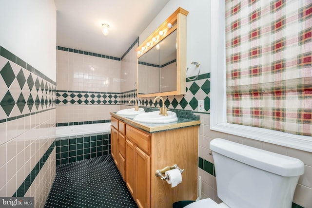 full bathroom with toilet, tile walls, vanity, and tiled tub