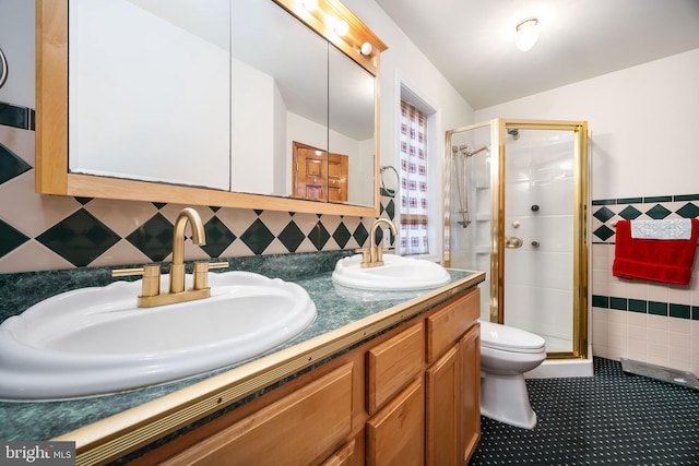 bathroom featuring tile walls, double vanity, a stall shower, and a sink