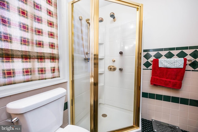 bathroom featuring toilet, tile walls, and a shower stall