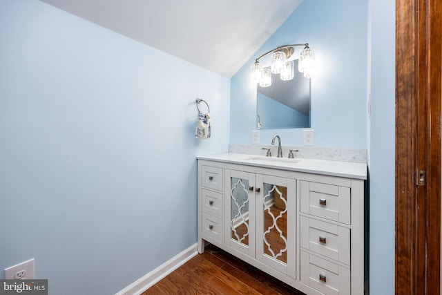 bathroom featuring vanity, vaulted ceiling, wood finished floors, and baseboards