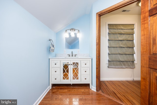 bathroom featuring vaulted ceiling, visible vents, baseboards, and wood finished floors