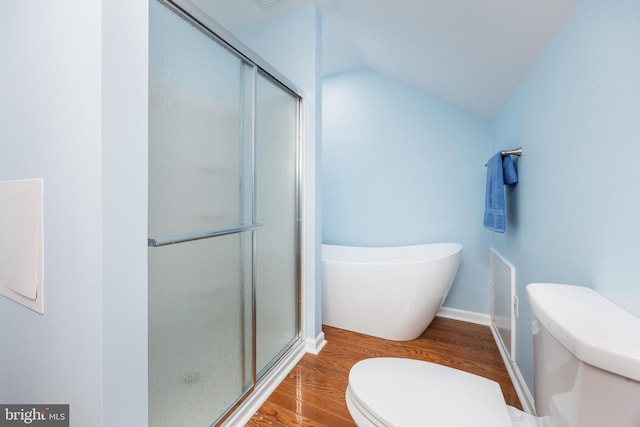 bathroom with a freestanding tub, toilet, a stall shower, wood finished floors, and vaulted ceiling