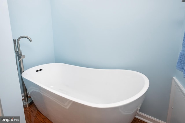 full bathroom featuring wood finished floors, baseboards, and a freestanding bath