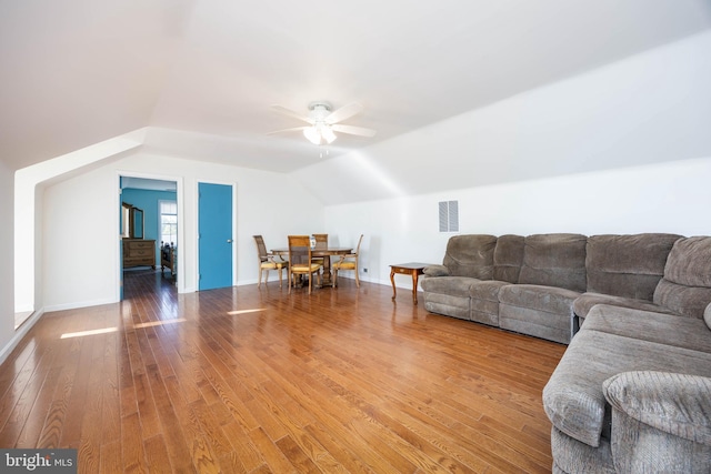 living area featuring visible vents, ceiling fan, baseboards, vaulted ceiling, and hardwood / wood-style flooring