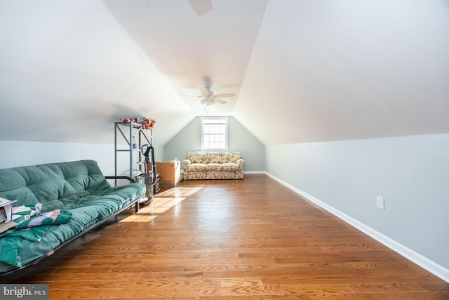 interior space with lofted ceiling, wood finished floors, baseboards, and ceiling fan