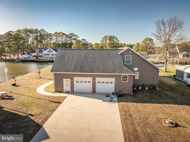 view of front of property with a front lawn, concrete driveway, a water view, and a shingled roof