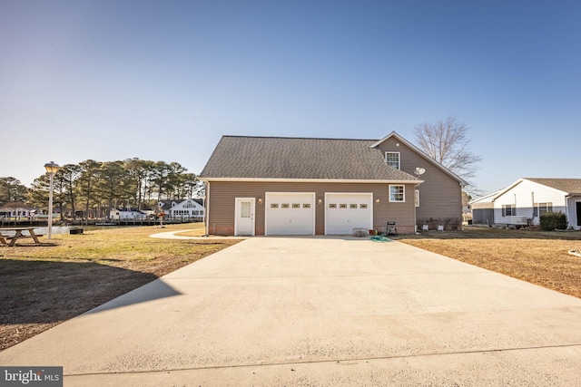 view of property exterior with an attached garage, a yard, driveway, and roof with shingles