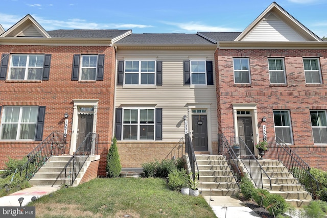 multi unit property with a shingled roof and brick siding