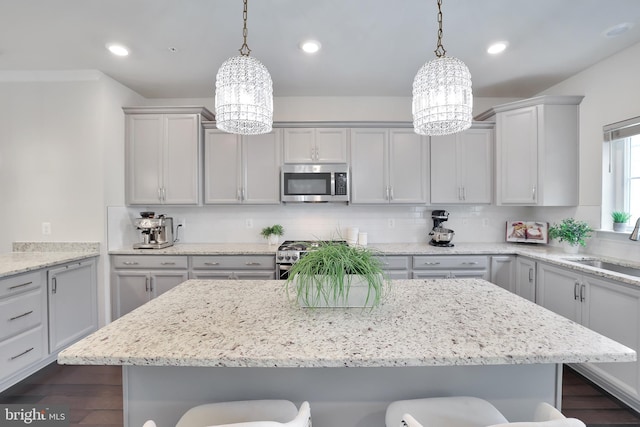 kitchen with a breakfast bar, tasteful backsplash, stainless steel appliances, and a notable chandelier