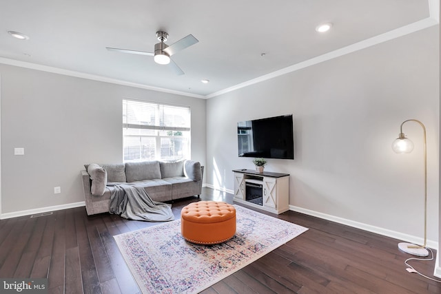 living area featuring ornamental molding, ceiling fan, dark wood-type flooring, and baseboards