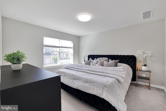 bedroom with visible vents, light carpet, and baseboards