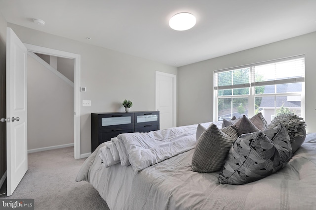 bedroom with light colored carpet and baseboards