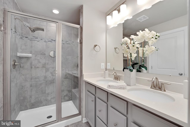 bathroom with a stall shower, visible vents, and a sink