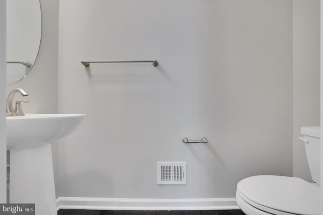 half bathroom with baseboards, visible vents, and toilet