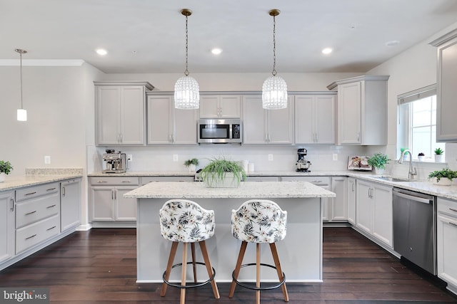 kitchen with appliances with stainless steel finishes, a center island, dark wood-type flooring, and a sink