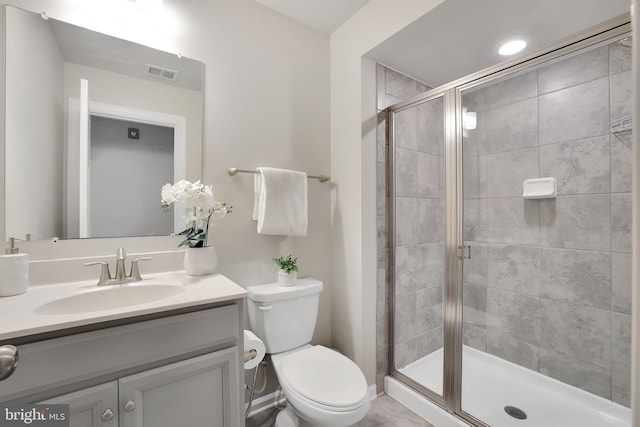 bathroom featuring toilet, vanity, a shower stall, and visible vents