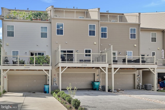 rear view of property featuring driveway, an attached garage, and central air condition unit