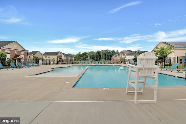 community pool featuring a residential view, a patio area, and fence