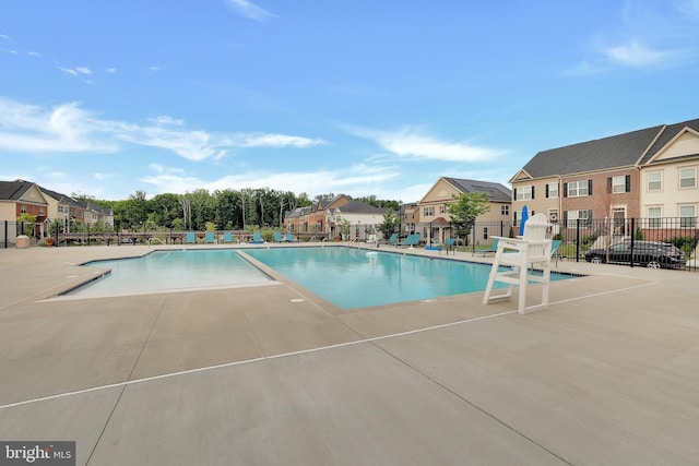 community pool featuring a patio, fence, and a residential view