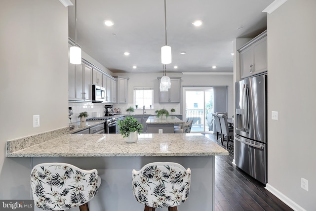 kitchen featuring dark wood-style floors, stainless steel appliances, tasteful backsplash, gray cabinetry, and a peninsula