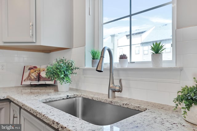 room details with light stone counters, backsplash, and a sink