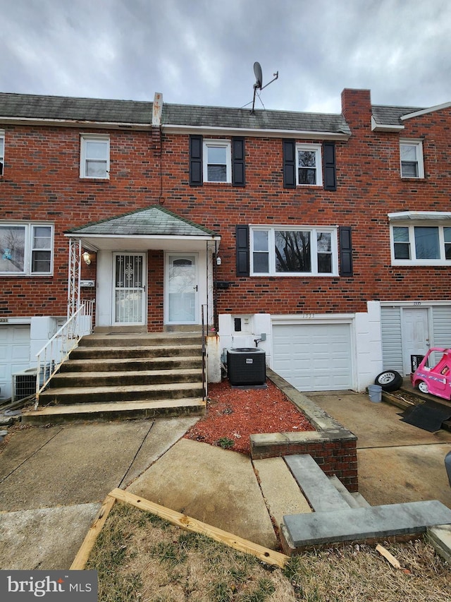 townhome / multi-family property with an attached garage, central AC unit, concrete driveway, and brick siding