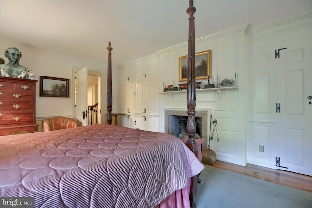 bedroom featuring a fireplace, crown molding, and wood finished floors