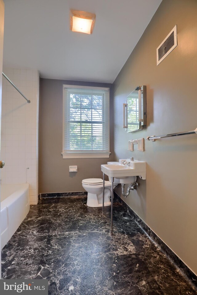 full bath featuring visible vents, toilet, vaulted ceiling, marble finish floor, and washtub / shower combination