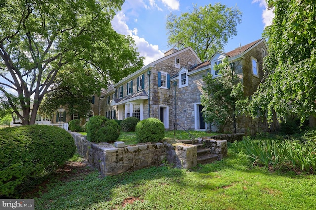 view of front facade with a front yard and stone siding