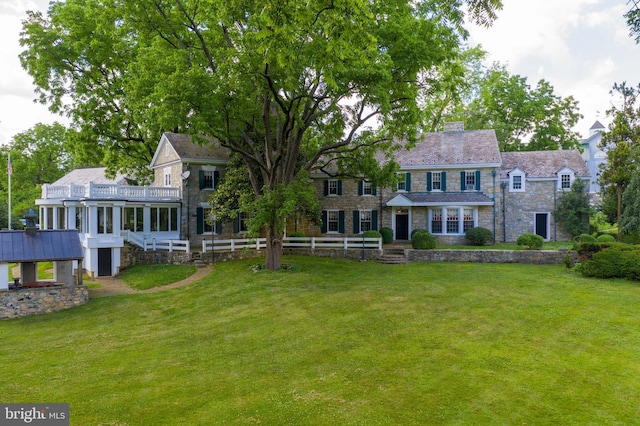 view of front facade featuring stone siding, a chimney, and a front lawn