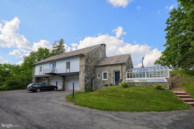 view of front of property with a high end roof, a front yard, a chimney, driveway, and an attached garage