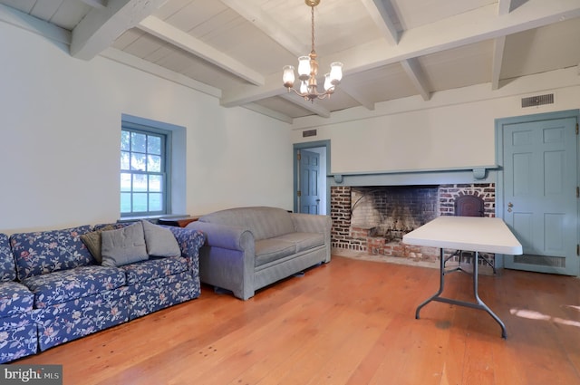 living room featuring visible vents, a brick fireplace, a chandelier, beamed ceiling, and hardwood / wood-style floors