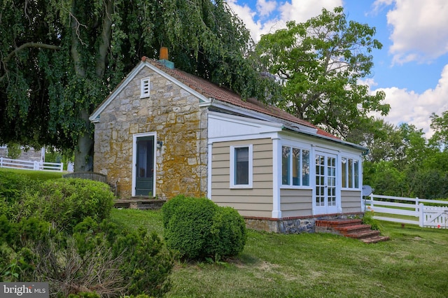 exterior space with fence, a lawn, and stone siding