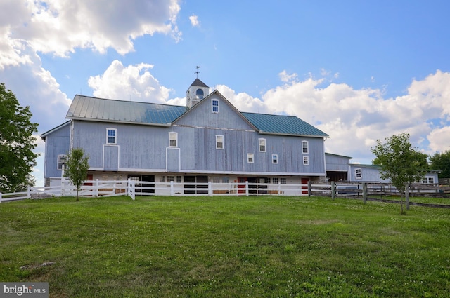 back of house with metal roof, a lawn, and fence