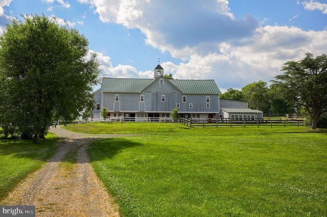 rear view of property featuring driveway, metal roof, a yard, and fence