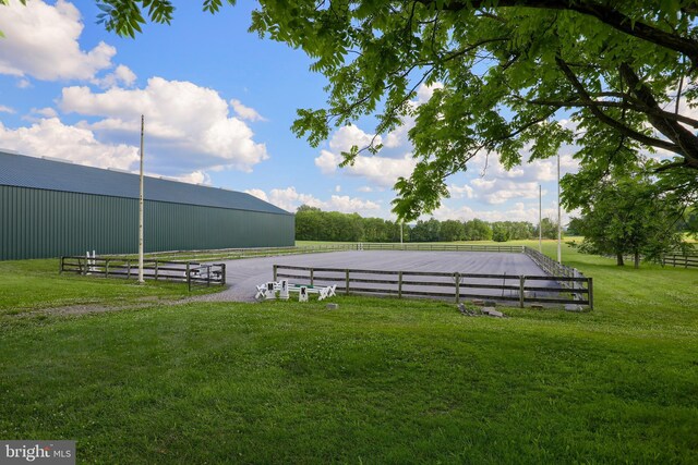 view of yard featuring an enclosed area, an outbuilding, an outdoor structure, and a rural view