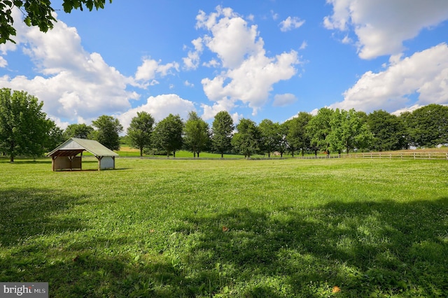 view of yard with a rural view, an outdoor structure, and fence