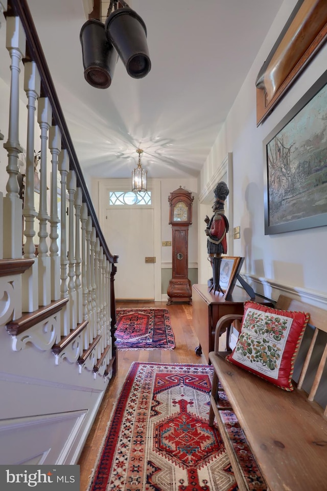 entryway featuring stairs, an inviting chandelier, and wood finished floors