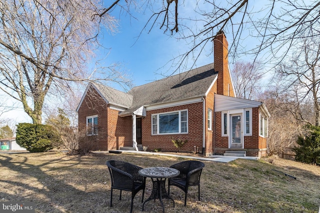 view of front of home with a shingled roof, a chimney, and brick siding