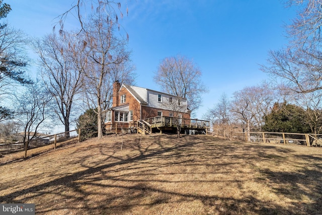 view of home's exterior with a yard, a chimney, fence, and a wooden deck