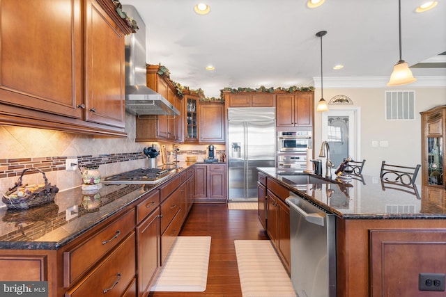 kitchen featuring range hood, stainless steel appliances, visible vents, brown cabinetry, and a sink