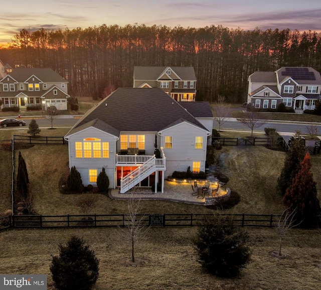 back of property with a patio area, a fenced front yard, stairway, and a lawn