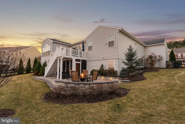 back of property at dusk with a yard, an outdoor fire pit, stairway, and a patio area