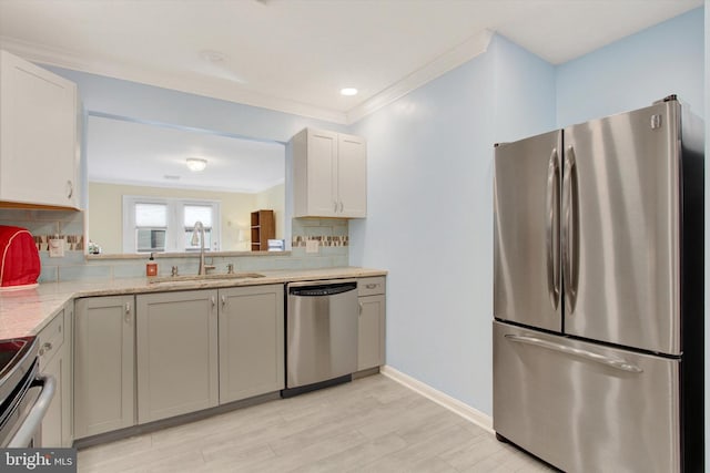 kitchen with a sink, light countertops, ornamental molding, appliances with stainless steel finishes, and tasteful backsplash